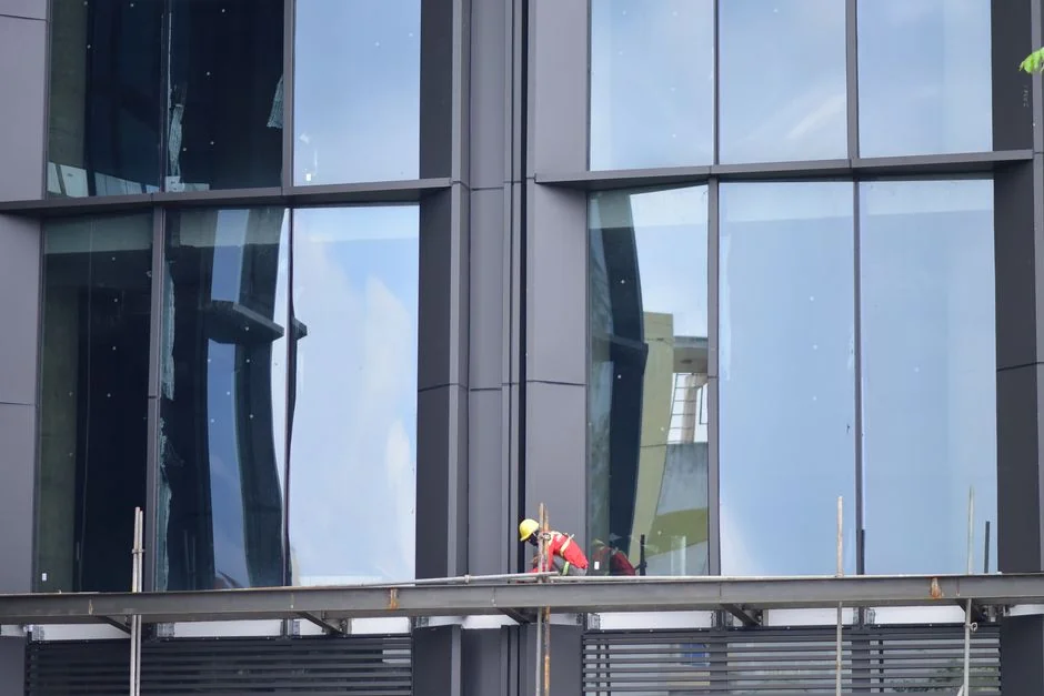 Two workers hanging to clean windows on a modern skyscraper facade.